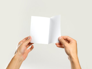 Male hands holding a white sheet of paper. Isolated on gray background. Closeup