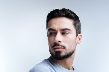 Incredulous look. Smart handsome young man feeling curious while standing with his head turned right and narrowing his eyes