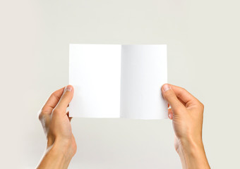 Male hands holding a white sheet of paper. Isolated on gray background. Closeup