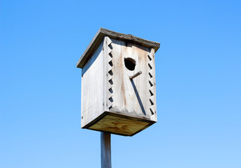 Beautiful wooden birdhouse. On the background of blue sky in a Sunny day.