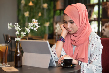 Happy young woman using tablet computer in a cafe while enjoy the coffee.