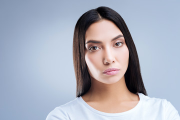 Tiresome championship. Strong serious professional sportswoman feeling tired and upset after the long competitions abroad while standing against the blue background and looking into the distance