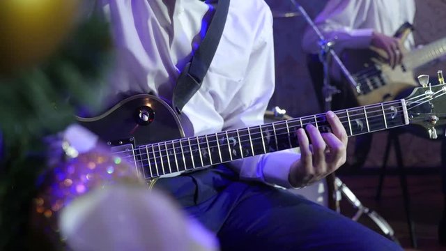 Guitarist Playing Electro Guitar on the background of Bass guitar player Close-up