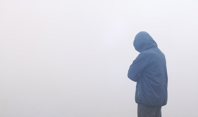 Ein anonymer Mann in Kapuzenjacke im Nebel