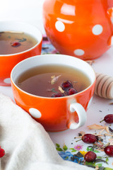 tea with herbs in red mugs on white background close-up.