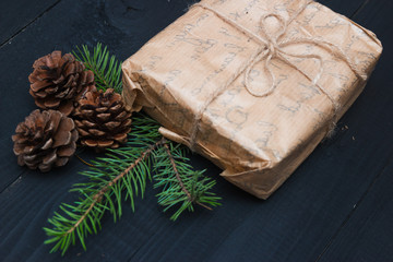 Wrapping rustic eco Christmas packages with brown paper, string and natural fir branches on dark background. Flat lay, free space.