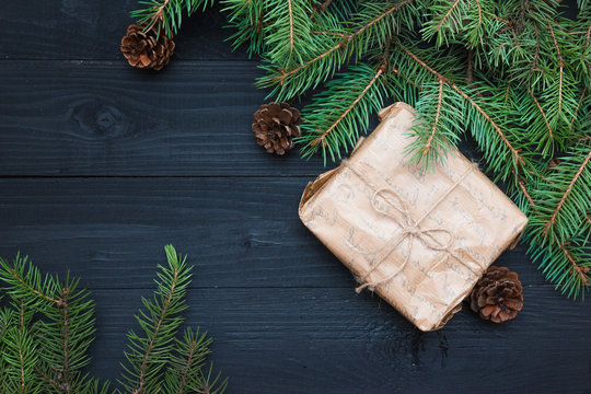 Wrapping rustic eco Christmas packages with brown paper, string and natural fir branches on dark background. Flat lay, free space.
