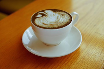 Hojicha latte with milk foam art on wooden table