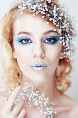 Creative makeup and beauty theme: a young girl with blue winter makeup on white background in Studio