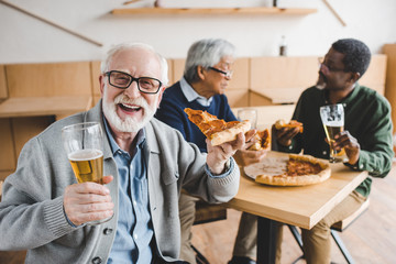 senior man eating pizza with beer