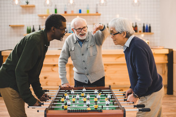 senior friends playing table football