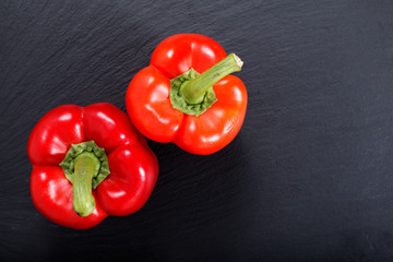 Organic red bell pepper on black slate stone plate with copy space