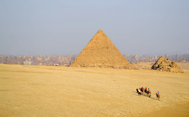 Fototapeta na wymiar Tourists ride on camels to the pyramids