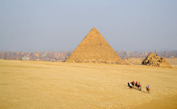 Tourists ride on camels to the pyramids