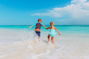 little boy and girl run play with water at beach