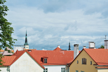 A view over red tile roofs of white and yellow houses of Tallin Old town, Estonia. Saint Olaf's Church at the background. Copy space for text.
