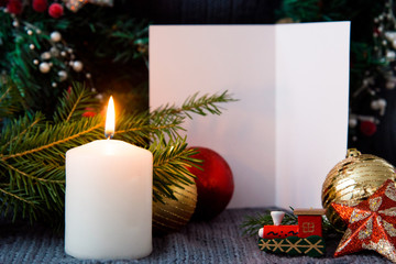 Christmas gold and red balls, xmas tree, candle and white card on dark wool background new year and holiday party