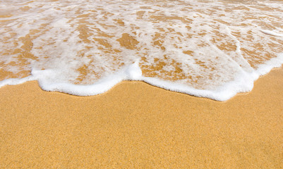 Fototapeta na wymiar foamy wave fine sand and sunshine reflection on the beach