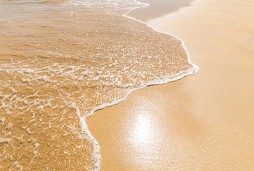 foamy wave fine sand and sunshine reflection on the beach
