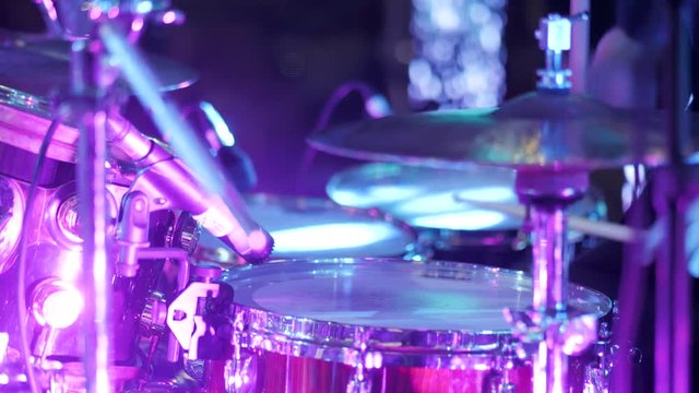 Young man playing electronic drums on stage. Concert. Neon light. Live music background. Drum kit on stage lights performance.Festival and show background. 4k