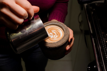 Fototapeta na wymiar Female hands making latte art in the concrete pot