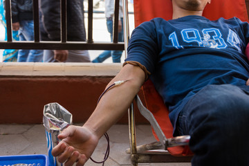 close up on arm of blood donor while donating blood