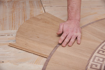 The carpenter installs one of the decorative elements of the parquet.