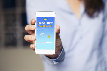 Weather forecast mobile phone app in a device screen. Woman hand holding it.