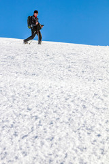 Man is snowshoe hiking through deep snow on sunny day