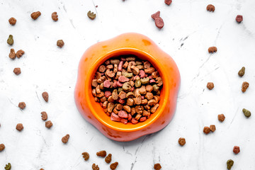 dry cat food in bowl on stone background top view