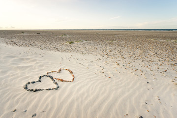 Pebbles arranged in shape of two hearts on sand beach ripples
