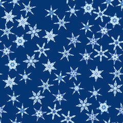 Seamless pattern with abstract colorful snowflakes on blue background. Chaotic, random, scattered winter motives. Vector illustration.