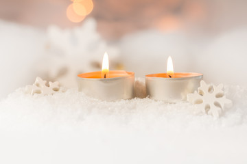 Zwei brennende Teelichte im Schnee