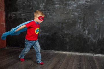 Fototapeta na wymiar boy superhero in a blue Cape red mask and a red t-shirt with a star
