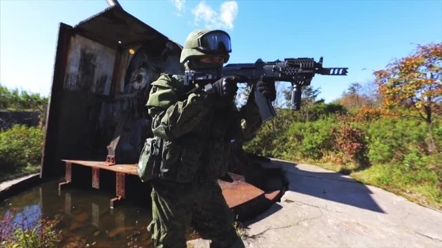 Soldier with AK rifle and modern uniform on old AAA post.