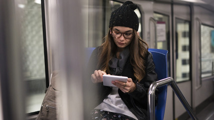 Young woman using digital tablet in metro
