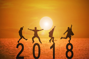 Silhouette group of peoples jumping on numbers 2018 over a beautiful sunset at the sea, concepts of news year and business target.