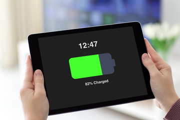 Female hands holding computer tablet with charged battery on screen