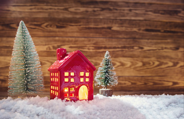 Old wooden planks with christmas trees and red house. Brown background with snow and snowflakes - Powered by Adobe
