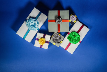 Set of multicolored gift boxes with bows on a blue background. top view