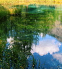 Beautiful reflection of trees and clouds in a quiet smooth surface of lake