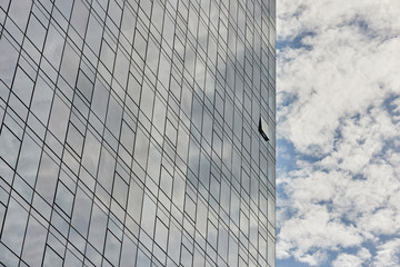 Glass facade business building reflecting blue sky with white clouds