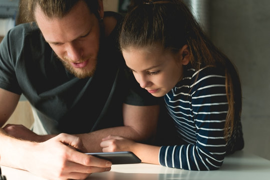 Father And Daughter Looking At Mobile Phone