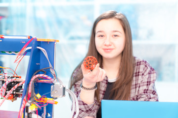 Girl schoolgirl with a 3D printer