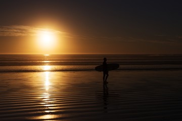 surfer with surfboard silhouette at the sunset beach