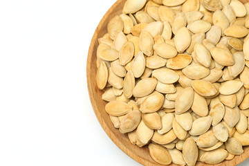 pumpkin seeds in wooden plate isolated on white background