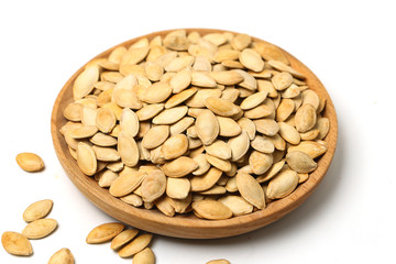 pumpkin seeds in wooden plate isolated on white background