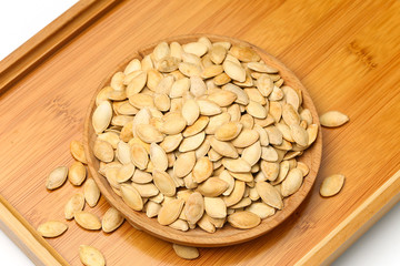 pumpkin seeds in wooden plate isolated on white background