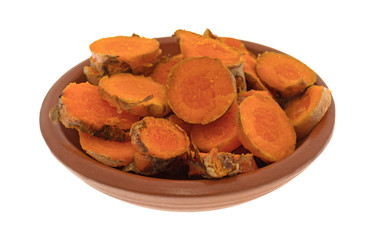 A small red clay bowl filled with slices of fresh turmeric isolated on a white background.