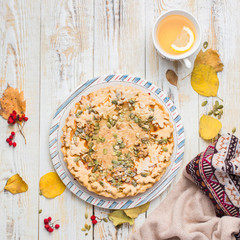 Autumn background with pumpkin pie, hot tea, yellowed leaves, book and rug. Perfect sunny autumn. A wooden light white autumn background for you. Copy Space. Place for text. Flat lay, top view